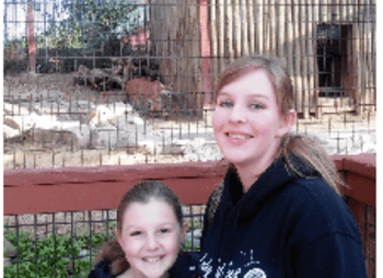 photo of Mrs. Carlson and her daughter in front of an animal enclosure at a zoo
